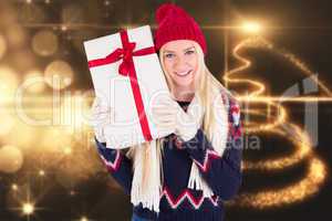 Composite image of festive blonde holding a gift