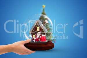 Composite image of hand holding snow globe