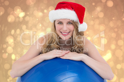 Composite image of festive fit blonde leaning on exercise ball