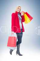 Happy blonde in winter clothes holding shopping bags