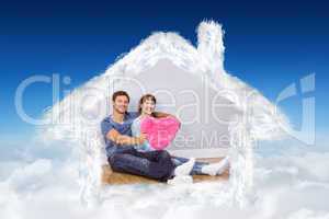 Composite image of couple holding a large heart