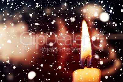Snow falling against candle burning