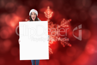 Composite image of happy brunette in santa hat showing white pos