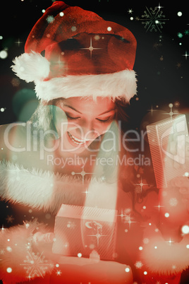 Composite image of pretty brunette in santa outfit opening gift