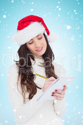 Composite image of festive brunette writing her christmas list