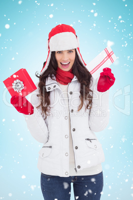 Composite image of festive brunette in winter clothes holding gi