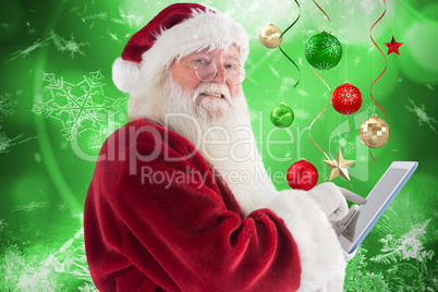 Composite image of santa uses a tablet pc and smiles into the camera