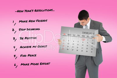 Composite image of businessman pointing at calendar in his hands