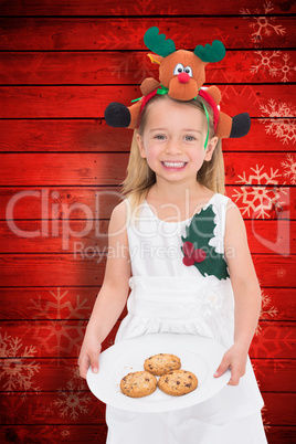 Composite image of festive little girl holding fresh cookies