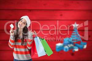 Composite image of smiling brunette holding credit card and shop