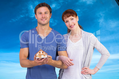 Composite image of couple holding a model house