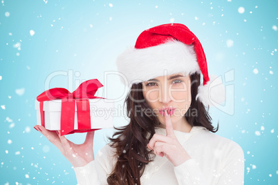 Composite image of festive brunette holding gift and keeping a s