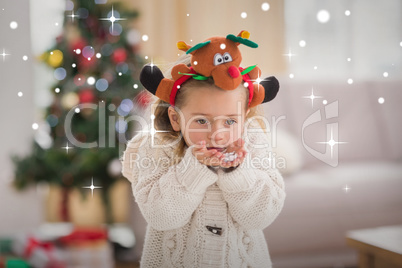 Composite image of festive little girl blowing over hands