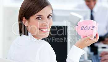 Composite image of happy businesswoman holding a piggybank