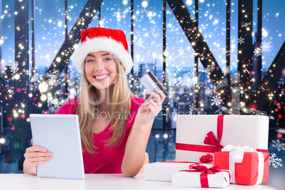 Composite image of festive blonde shopping online with tablet