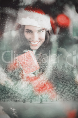 Composite image of festive brunette pressing gift at christmas