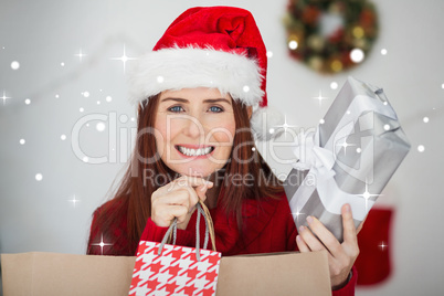 Composite image of festive redhead holding christmas gifts