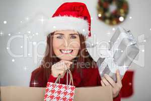 Composite image of festive redhead holding christmas gifts