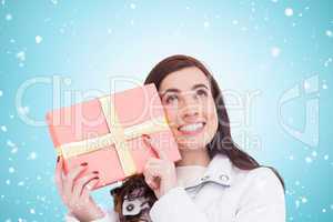 Composite image of portrait of a happy brunette holding gift