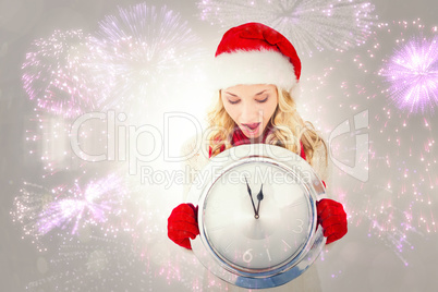 Composite image of festive blonde holding large clock