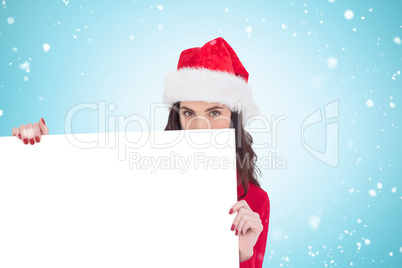 Composite image of beauty brunette in santa hat showing white po