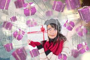 Composite image of festive brunette holding white and red gift