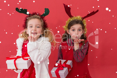 Composite image of festive little girls holding gifts