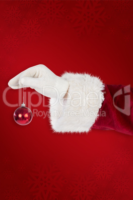 Composite image of santas hand is holding a christmas bulb