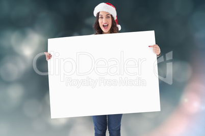 Composite image of pretty brunette in santa hat pointing white p