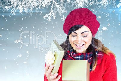 Composite image of happy brunette opening christmas gift