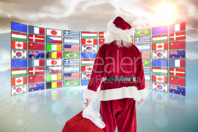 Composite image of santa carrying sack of gifts