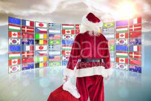 Composite image of santa carrying sack of gifts