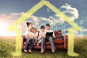 Composite image of happy family using the laptop in a field