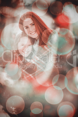 Composite image of festive mother and daughter wrapped in blanke