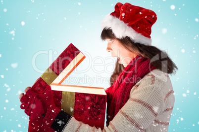 Composite image of festive brunette opening a glowing christmas