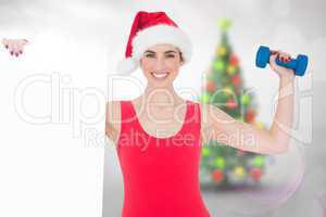 Composite image of festive fit brunette holding page and dumbbel