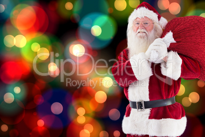 Composite image of santa carries his red bag and smiles