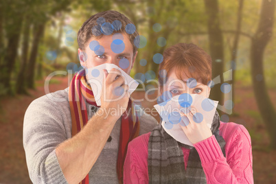 Composite image of couple blowing noses into tissues