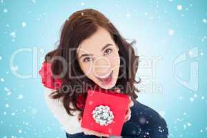 Composite image of excited brunette sitting holding red gift