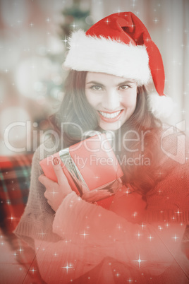 Composite image of festive brunette pressing gift at christmas Composite image of festive brunette pressing gift at christmas