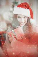 Composite image of festive brunette pressing gift at christmas