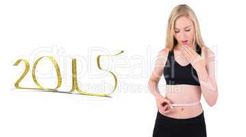 Composite image of fit young blonde looking at measuring tape