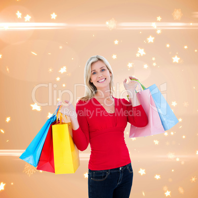 Composite image of happy blonde holding shopping bags