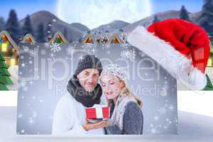 Composite image of happy winter couple with gift