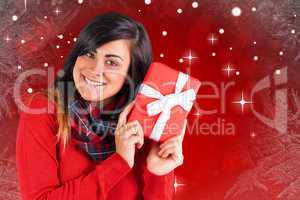 Composite image of excited brunette holding red gift