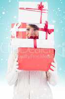 Composite image of festive young woman holding pile of gifts
