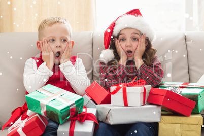 Composite image of festive siblings surrounded by gifts