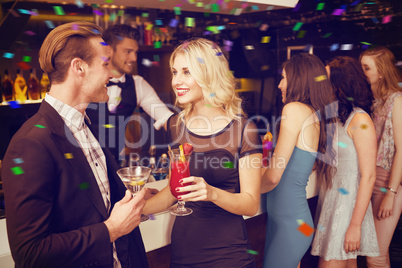 Composite image of attractive friends drinking cocktails togethe