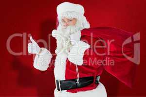 Composite image of positive santa with his sack and thumbs up