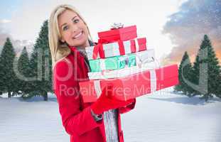 Composite image of festive blonde holding many gifts